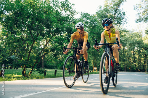 Couple riding bicycles outside of the city and wearing helmets and sunglasses photo