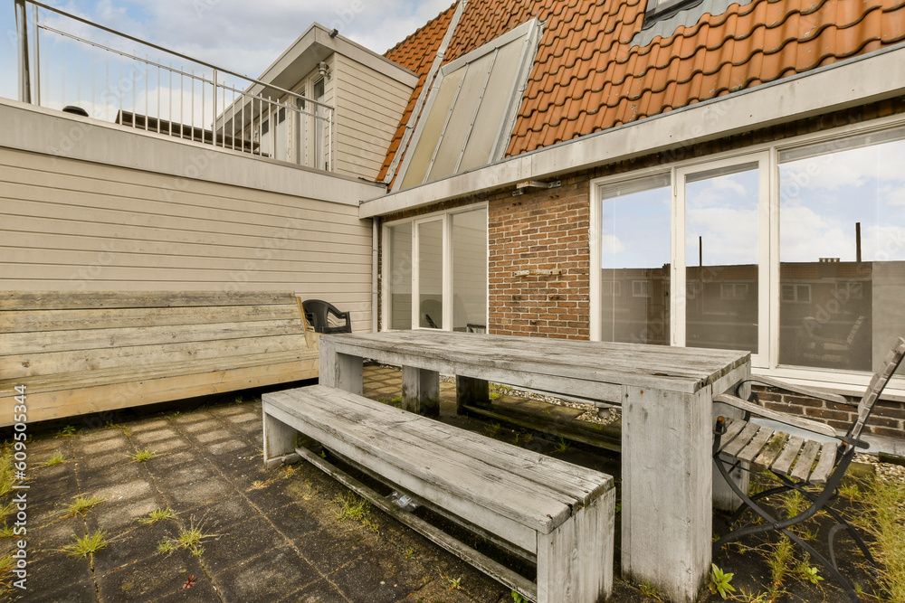 an outside area with a wooden bench and some plants on the ground in front of a brick building that is being used as a an outside area with a wooden bench and some plants on the ground in front of a brick building that is being used as a