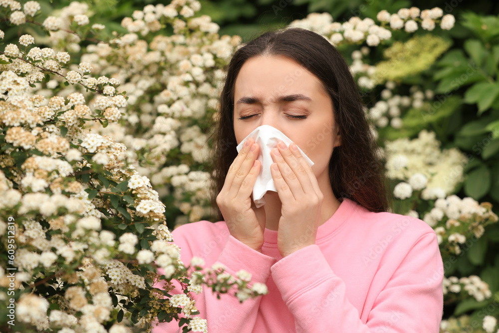 Woman suffering from seasonal pollen allergy near blossoming tree on spring day Woman suffering from seasonal pollen allergy near blossoming tree on spring day
