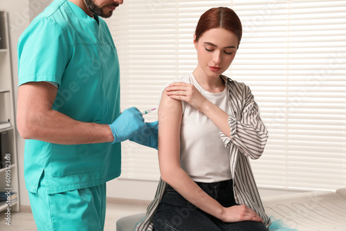 Doctor giving hepatitis vaccine to patient in clinic