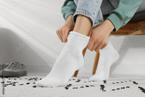 Woman putting on white socks at home, closeup photo