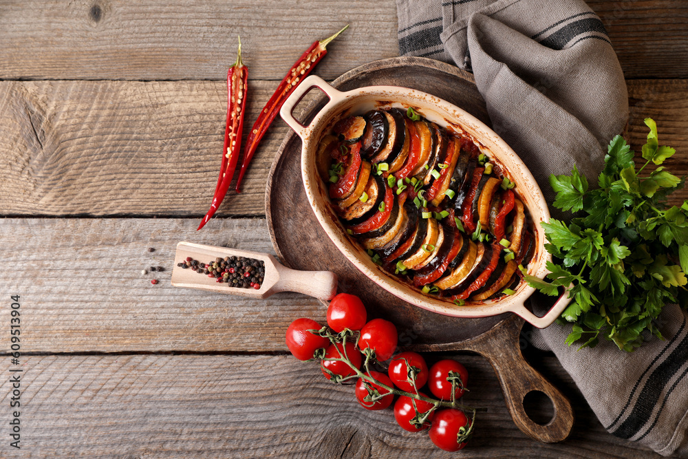 Delicious ratatouille and ingredients on wooden table, flat lay. Space for text