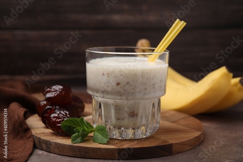 Glass of delicious date smoothie, mint and dried fruits on brown table