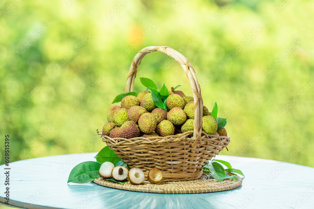 Chinese Green Lychee fruit in wooden basket over blur greenery background, Green Lychee or Chinese Cherry fruit over green natural Blur background.