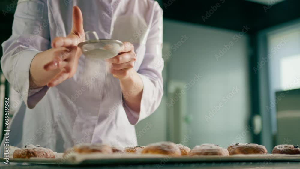 attractive baker sprinkles powdered sugar on ready freshly baked hot fragrant buns baking production bakery