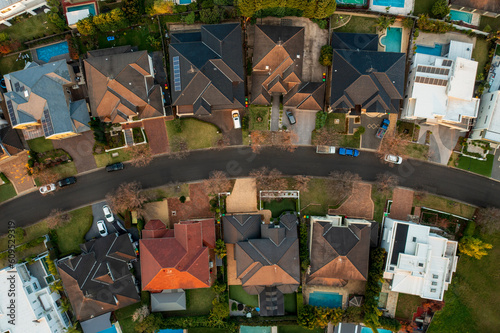 Aerial top top down view of upmarket houses on a curved street in the fading winter light in suburban Sydney, Australia.