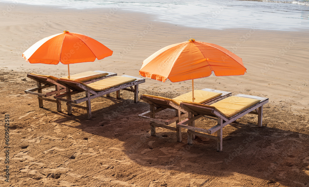 Empty sunbeds with umbrellas on the sandy beach of the tropical island of Sri Lanka. Beautiful sunny day.