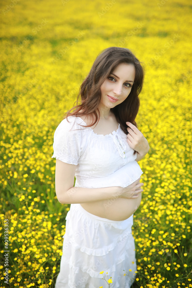 Pregnant woman in a dress in a field of flowers Pregnant woman in a dress in a field of flowers