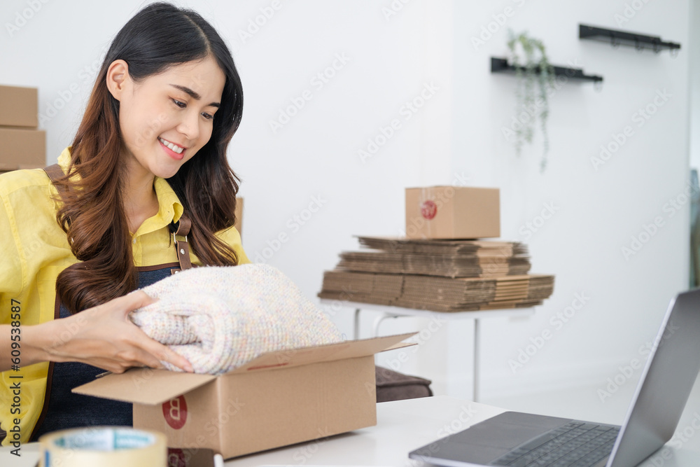 Start up small business owner, online seller packing new clothing in cardboard box for delivery. E-commerce, fashion and technology Start up small business owner, online seller packing new clothing in cardboard box for delivery. E-commerce, fashion and technology