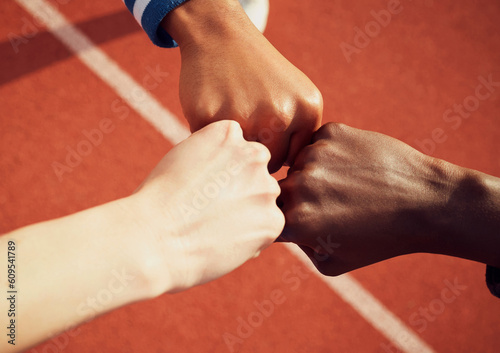 People, diversity and fist bump in fitness for teamwork, unity or trust together on stadium track above. Hands of group touching fists in team building for sports motivation, agreement or goals photo