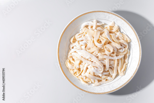 Homemade noodle for lagman in white bowl on grey background, isolated, top view	
