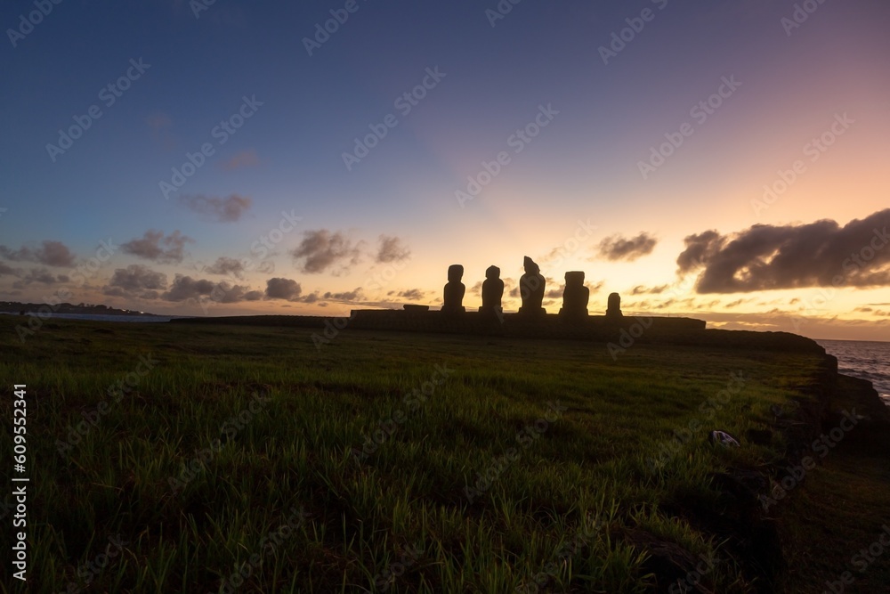 Fototapeta premium Sunset at Famous Tahai Archaeological site with Row of Moai Statues. Hanga Roa Waterfront, Easter Island Chile, Rapa Nui Pacific Coastline