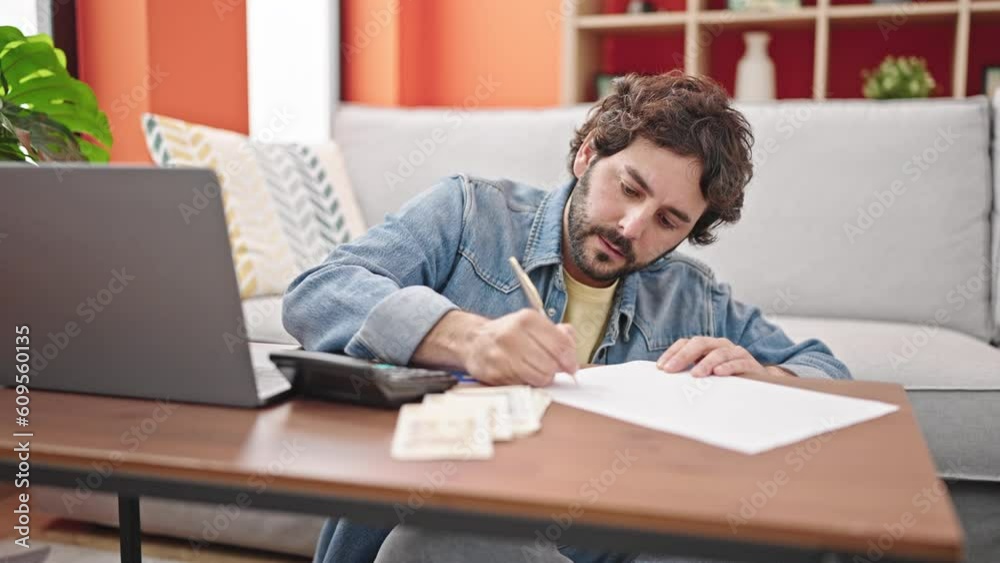 Young hispanic man writing on paper accounting denmark krone banknotes at home