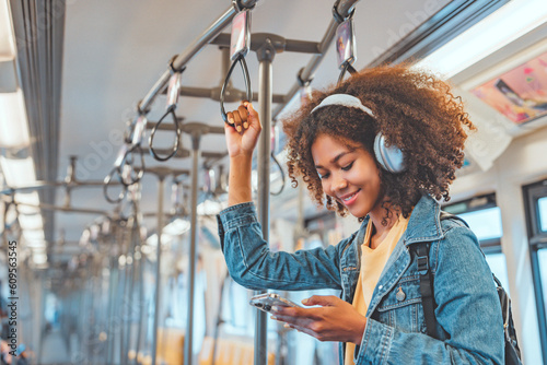 Obraz na plátne Happy young African American woman passenger listening music via smart mobile ph