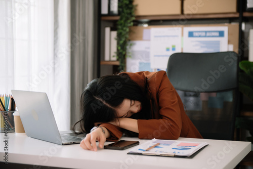 Overworked young Asian businesswoman office worker suffering from neck pain after had a long day at her office desk.