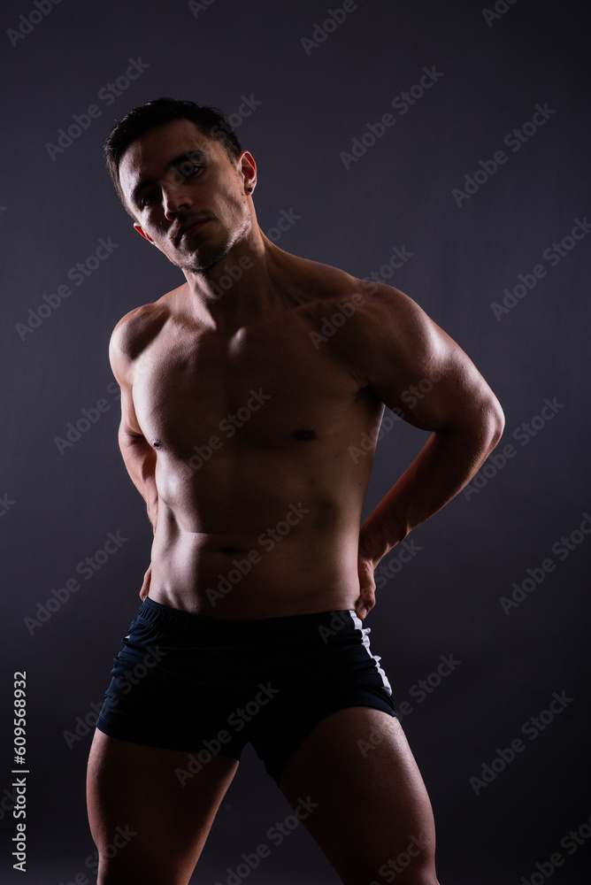 Muscular shirtless young man standing confident, front view, looking at camera Muscular shirtless young man standing confident, front view, looking at camera