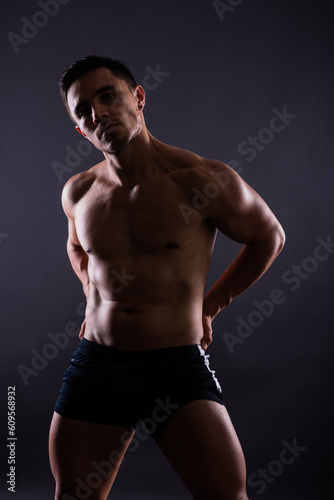 Muscular shirtless young man standing confident, front view, looking at camera