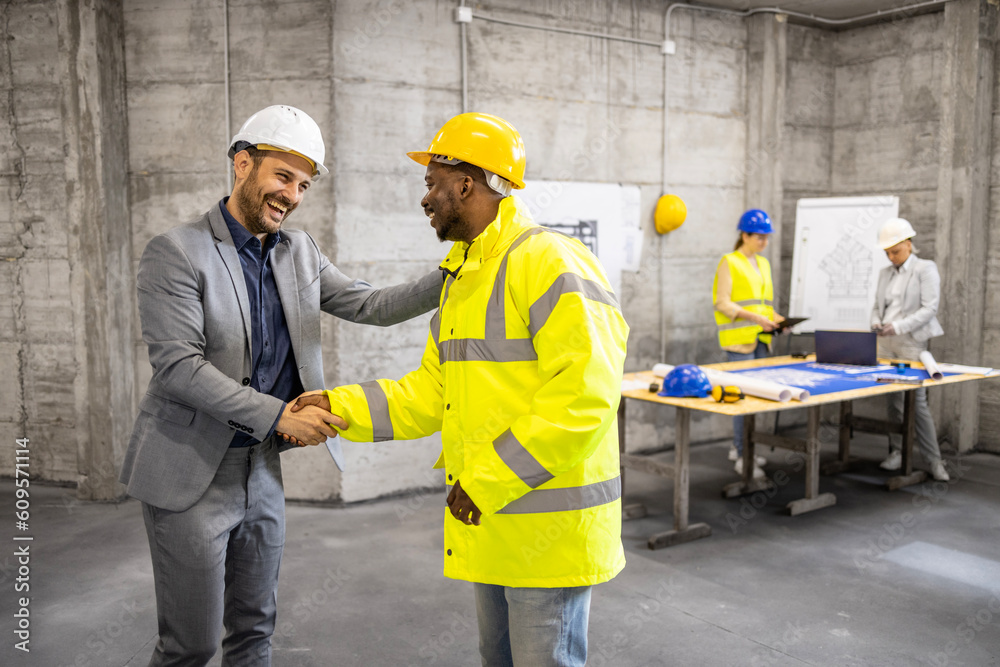 Contractor shaking hand with construction engineer st building site. Contractor shaking hand with construction engineer st building site.