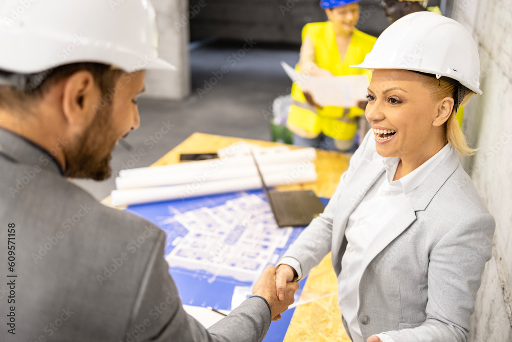 Team of experienced architects and civil engineers analyzing and looking at building plant at construction site.