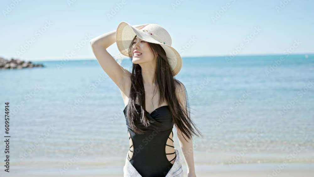 Young chinese woman tourist smiling confident wearing swimsuit and summer hat at seaside Young chinese woman tourist smiling confident wearing swimsuit and summer hat at seaside