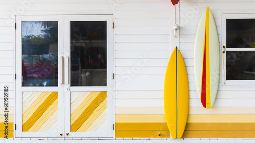 Colorful facade wall with surfboards hanging on it with door and window background. © bunditinay