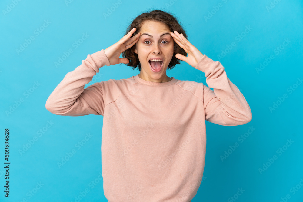Young English woman isolated on blue background with surprise expression