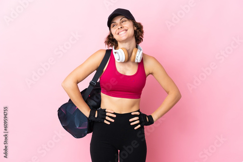 Young sport woman with sport bag over isolated background posing with arms at hip and smiling © luismolinero