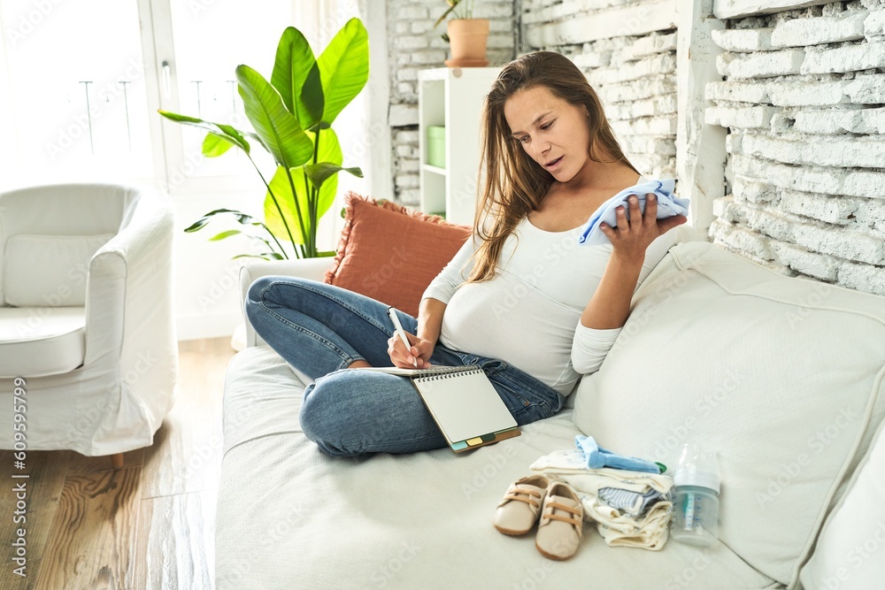 Pregnant woman on sofa, lovingly prepares for baby's arrival. Pregnant woman on sofa, lovingly prepares for baby's arrival.