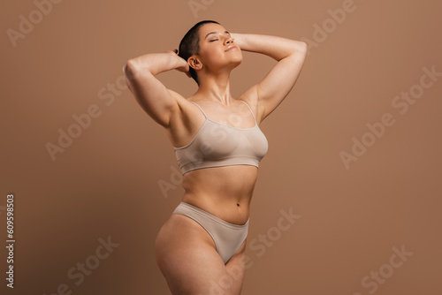 Valokuva Beautiful young short hair woman in underwear holding hands behind head against