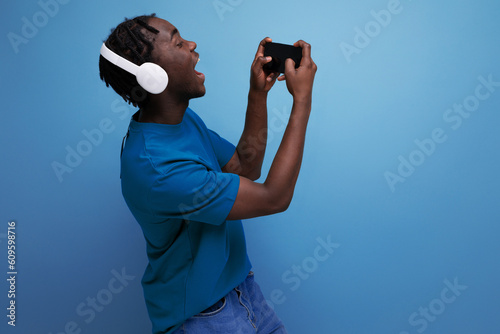 young african man watching video with wireless headphones and mobile phone