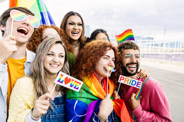 Happy group of young people celebrating gay pride day festival together. Millennial homosexual adult friends enjoying celebration about equal rights and freedom