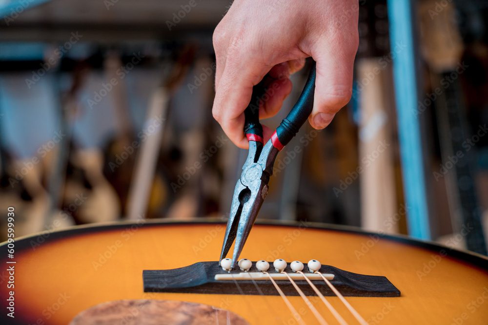 Young musician changing strings on a classical guitar in a guitar shop