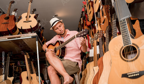 Young musician testing classical guitar in a guitar shop
