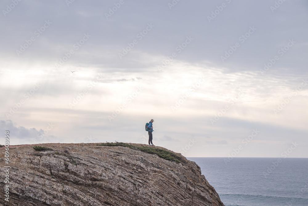 Fototapeta premium Travel enthusiast enjoys his freedom in the Portuguese countryside on the Atlantic coast observing the endless sea and the shapes of the cliffs. Wandering the Fisherman Trail