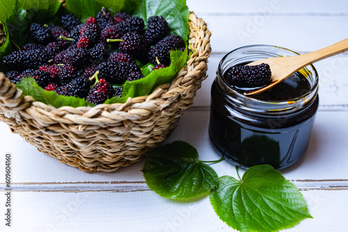 Mulberry fruit, mulberry molasses in glass bowl and fresh mulberry in basket, wooden background.