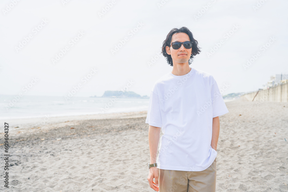 夏の海岸を歩くサングラスをかけた男性