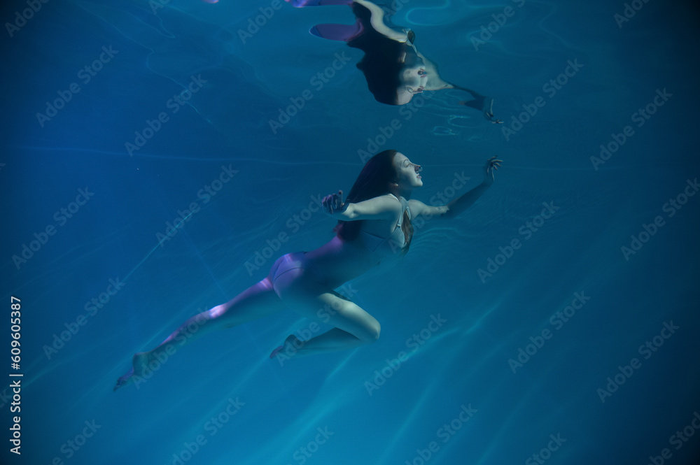 Obraz premium a girl under water, in an aquarium, in a pool in flesh-colored underwear naked swims like a mermaid
