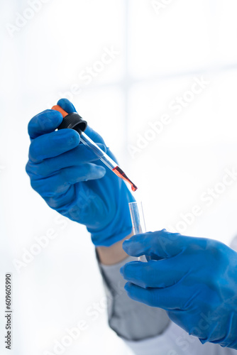 Doctor hand taking a blood sample tube from a rack with machines of analysis in the lab background, Technician holding blood tube test in the research laboratory.