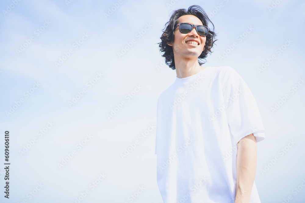 夏の海岸を歩くサングラスをかけた男性 夏の海岸を歩くサングラスをかけた男性