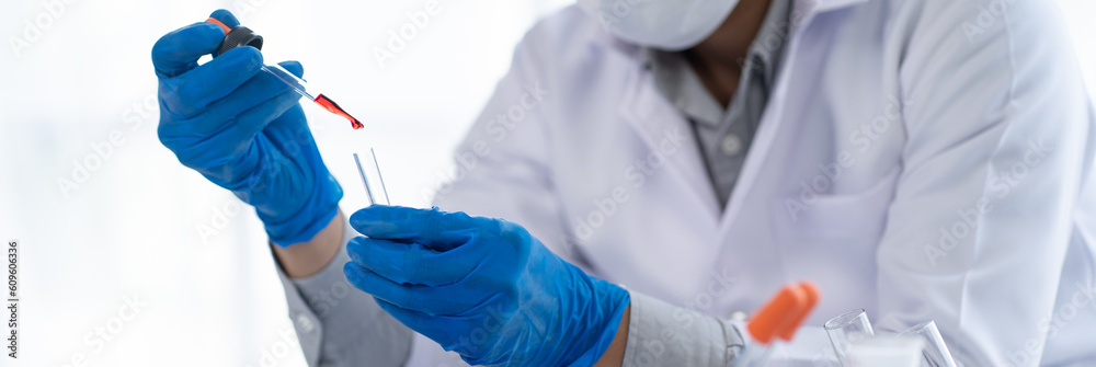 Doctor hand taking a blood sample tube from a rack with machines of analysis in the lab background, Technician holding blood tube test in the research laboratory. Doctor hand taking a blood sample tube from a rack with machines of analysis in the lab background, Technician holding blood tube test in the research laboratory.