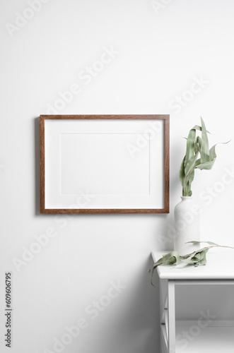 Blank frame mockup on white wall with dry eucalyptus plant, blank mockup with copy space