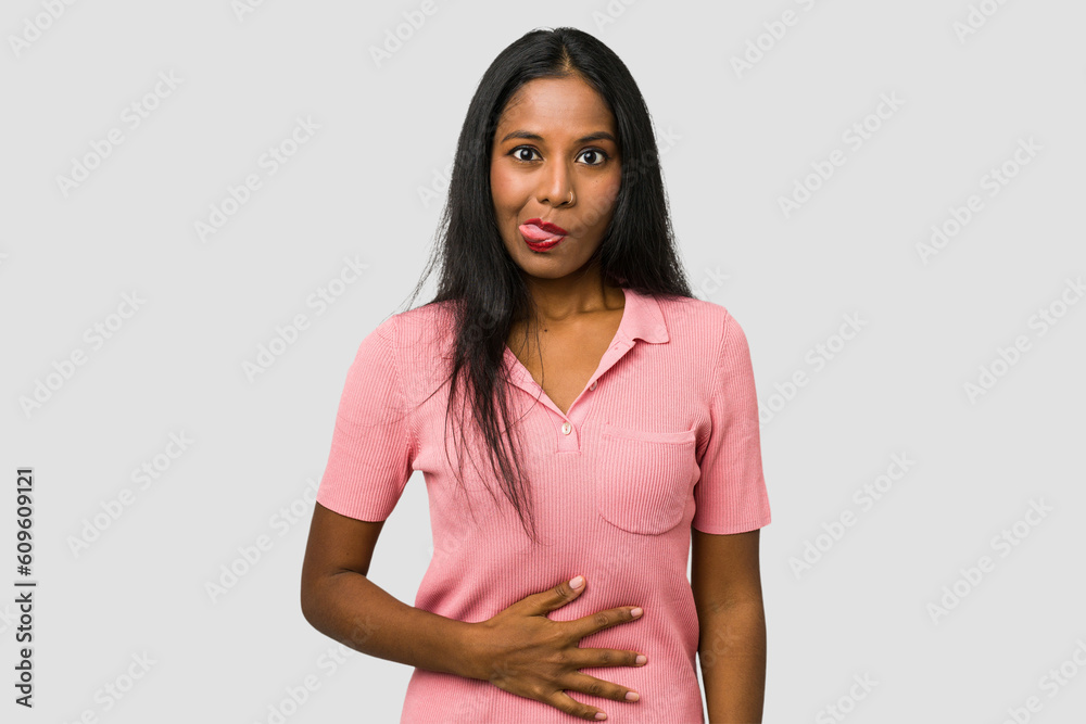 Young Indian woman cut out isolated on white background touches tummy, smiles gently, eating and satisfaction concept. Young Indian woman cut out isolated on white background touches tummy, smiles gently, eating and satisfaction concept.
