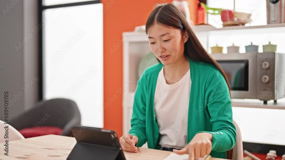 Young chinese woman having online lesson using touchpad at dinning room Young chinese woman having online lesson using touchpad at dinning room