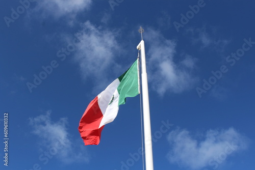 Mexico flag and white flag pole isolated with a few clouds 