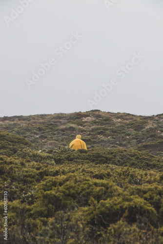 Wandering in heavy rain and wearing a raincoat along the Fisherman Trail in the southern part of Portugal during rainy weather heading to Cape St. Vicente. Rough landscape