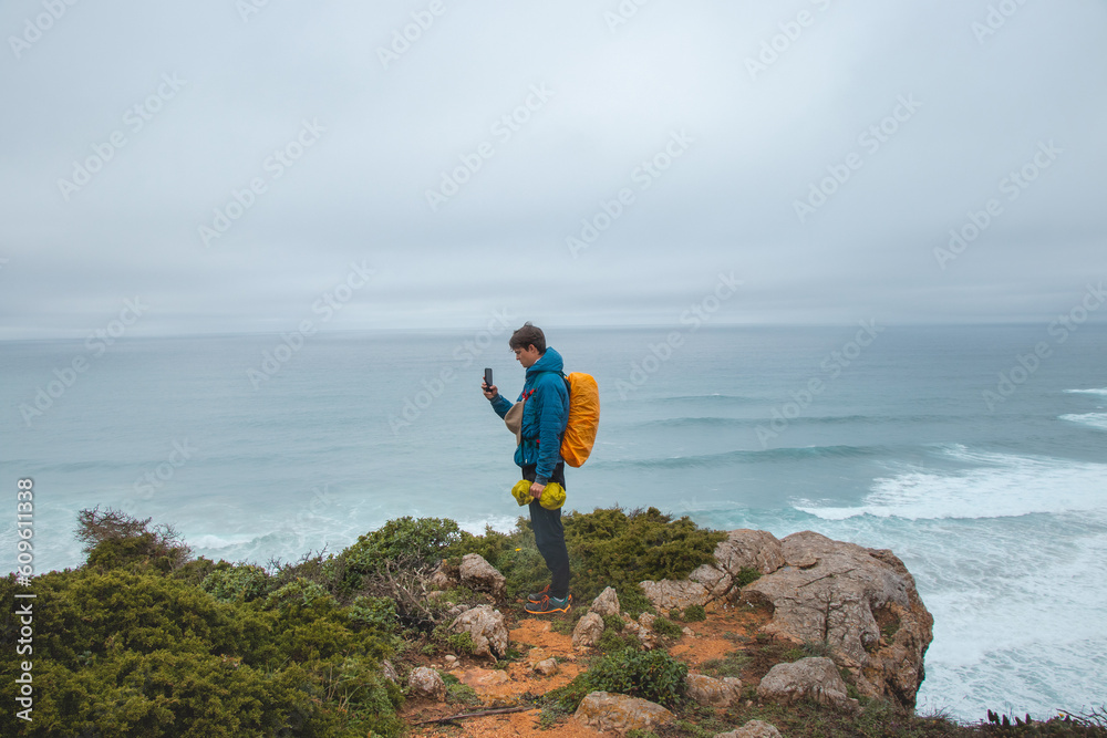Adventurer wandering the Fisherman Trail in the Algarve region of Portugal takes pictures of the ocean, which has come to life during the rainy weather. The power of water