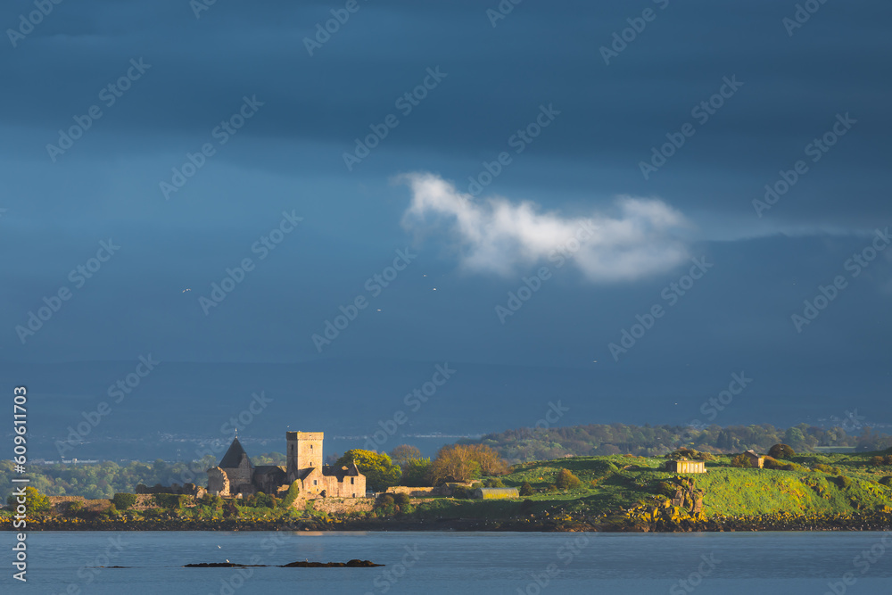 Moody, dramatic view of golden light over the Firth of Forth onto the historic medieval monastery Inchcolm Abbey, from Aberdour, Fife, Scotland, UK.
