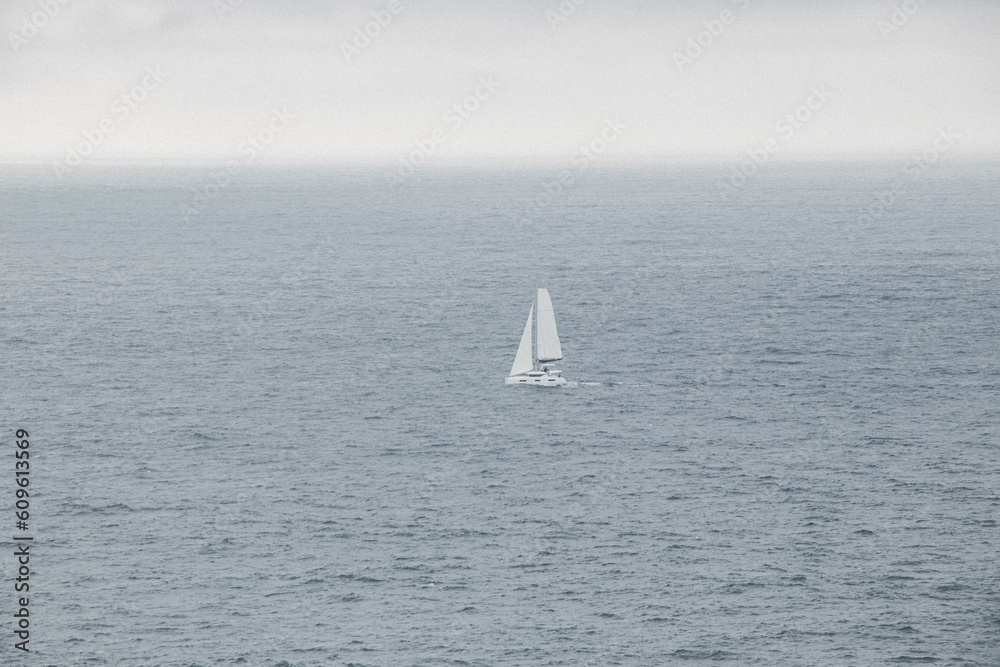 White sailfish sails through the stormy Atlantic Ocean in rainy weather in southern Portugal