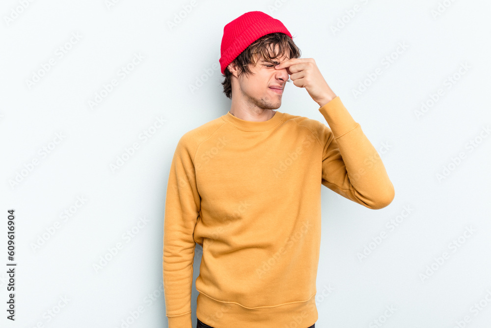 Young caucasian man isolated on blue background having a head ache, touching front of the face. Young caucasian man isolated on blue background having a head ache, touching front of the face.