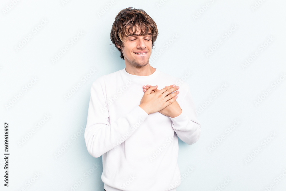 Young caucasian man isolated on blue background has friendly expression, pressing palm to chest. Love concept. Young caucasian man isolated on blue background has friendly expression, pressing palm to chest. Love concept.